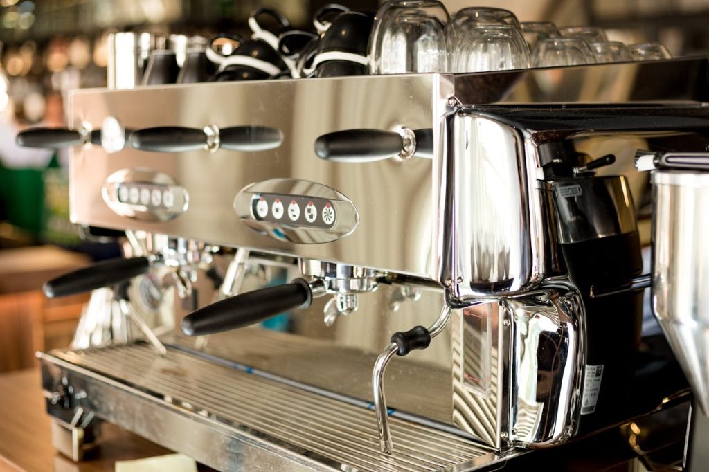 A sleek and modern stainless steel coffee machine in a contemporary cafe setting.
